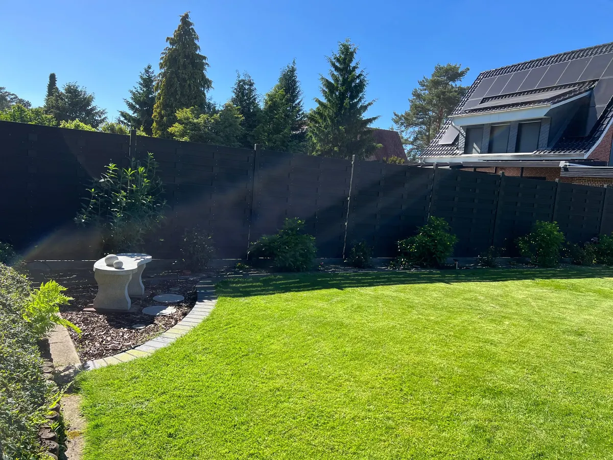 Neu angelegter Garten mit Sichtschutz, bepflanztem Beet und frischem Rollrasen
