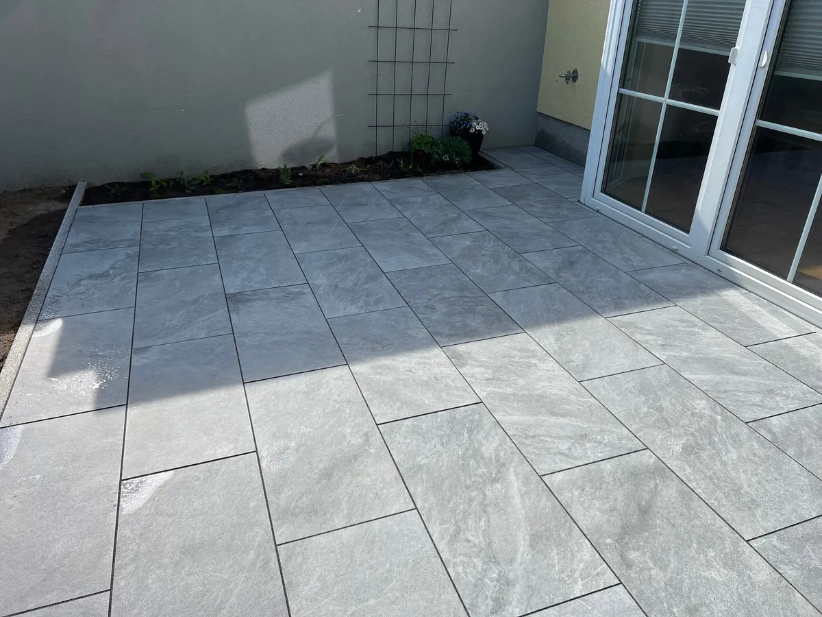 Neu verlegte Plattenterrasse mit Granitborden an einem Wohnhaus