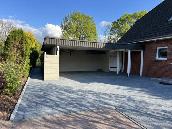 Fertig gepflasterte Einfahrt aus anthrazitfarbenem Betonpflaster vor dem Doppelcarport