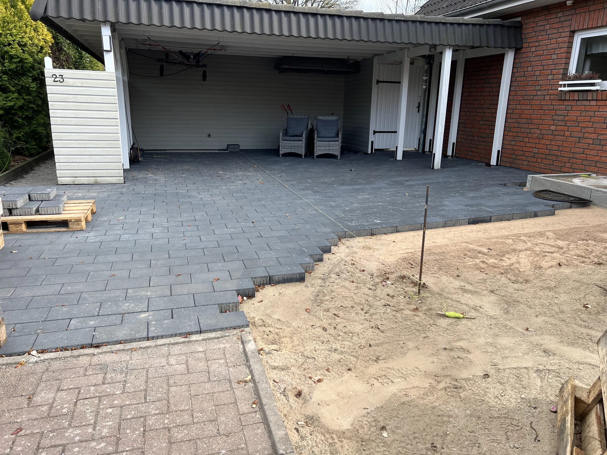 Während der Arbeiten: halb verlegte Pflasterfläche unter dem Carport mit offenem Sandplanum
