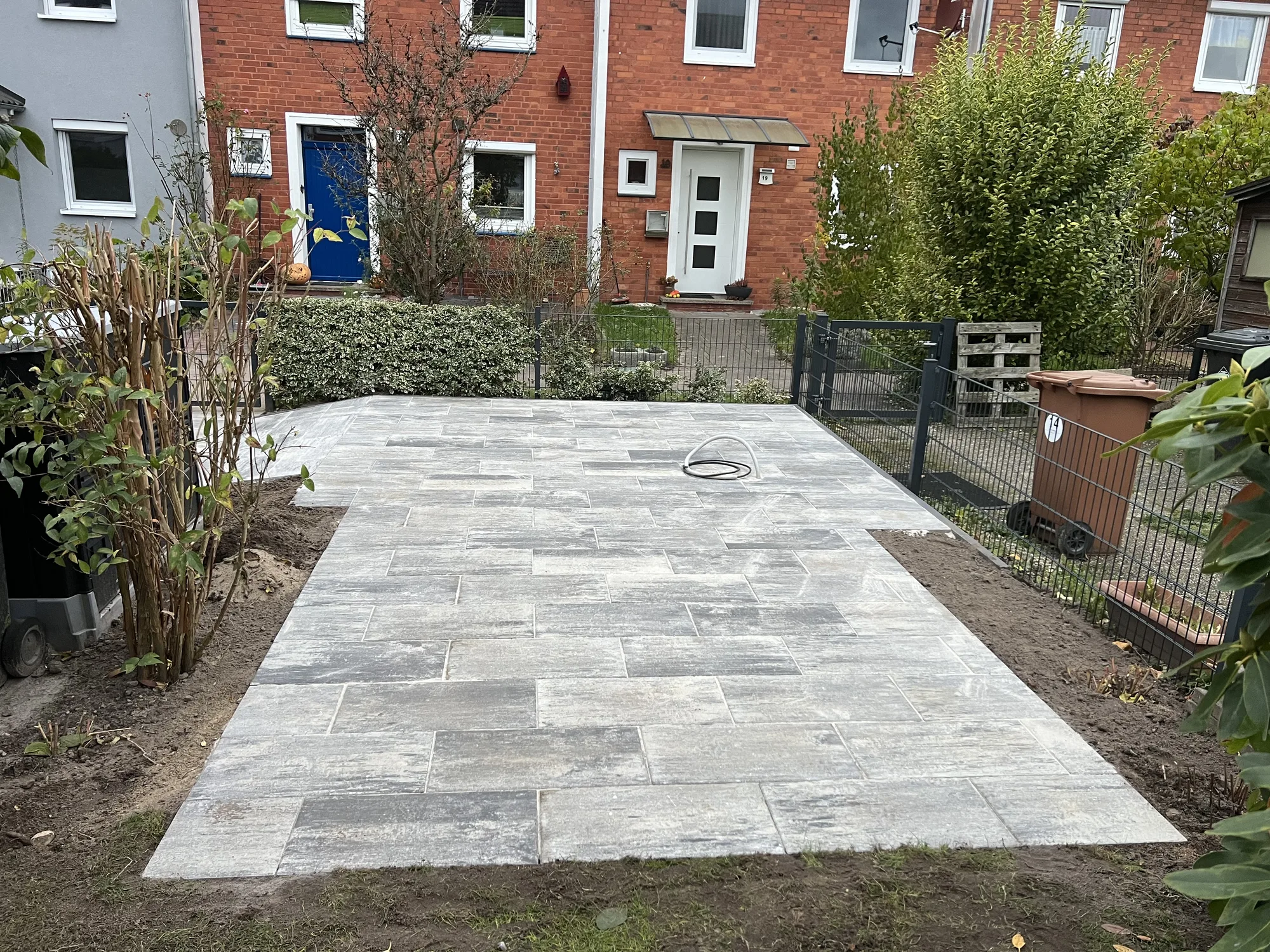Frisch verlegte großformatige Terrassenplatten in Grau mit vorbereiteten Pflanzstreifen an den Rändern