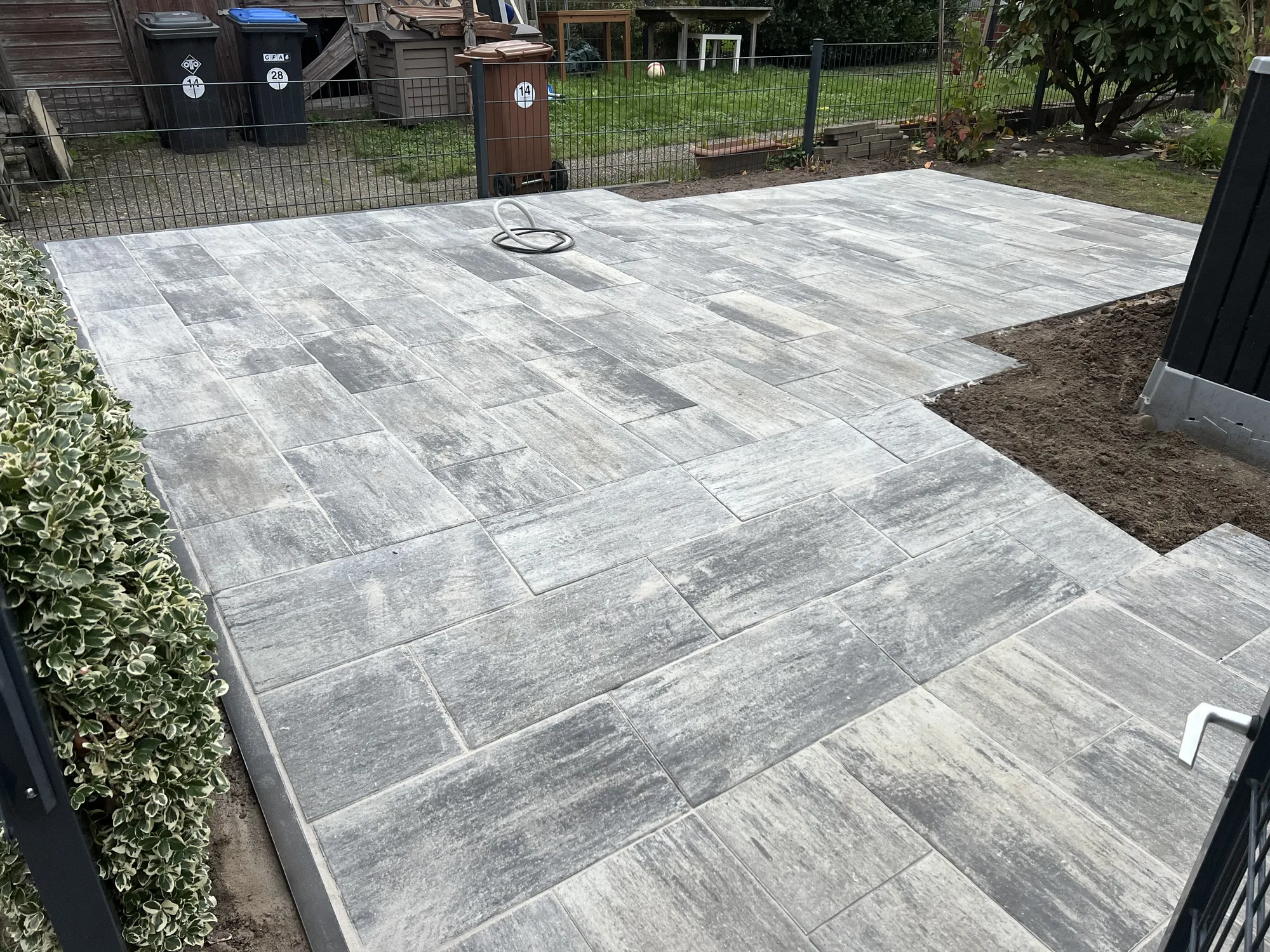 Fertig verlegte Terrassenfläche aus großformatigen Betonplatten in Grau-Anthrazit mit sauberer Randeinfassung