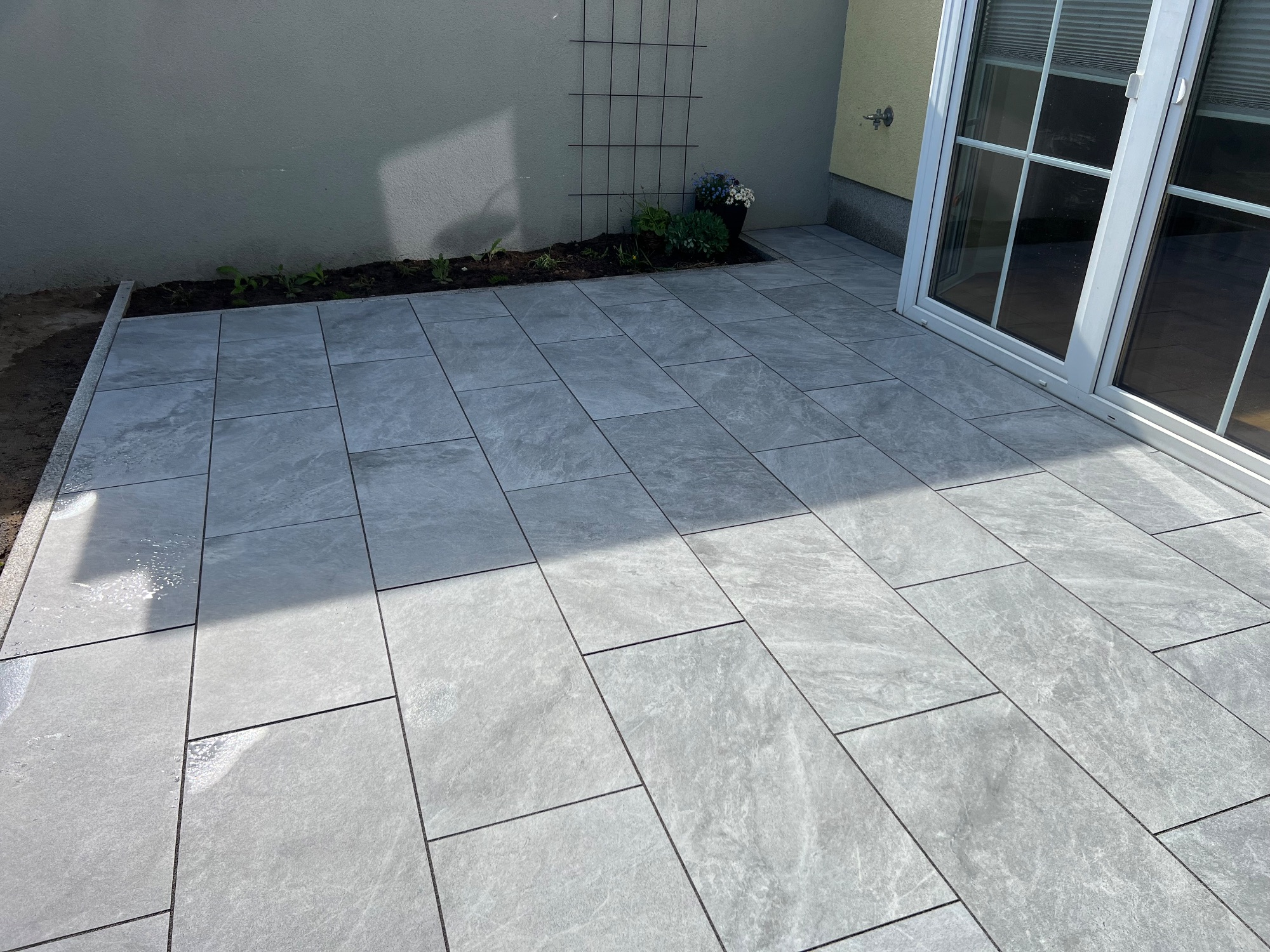 Fertige Terrasse mit großformatigen Betonplatten in Grautönen