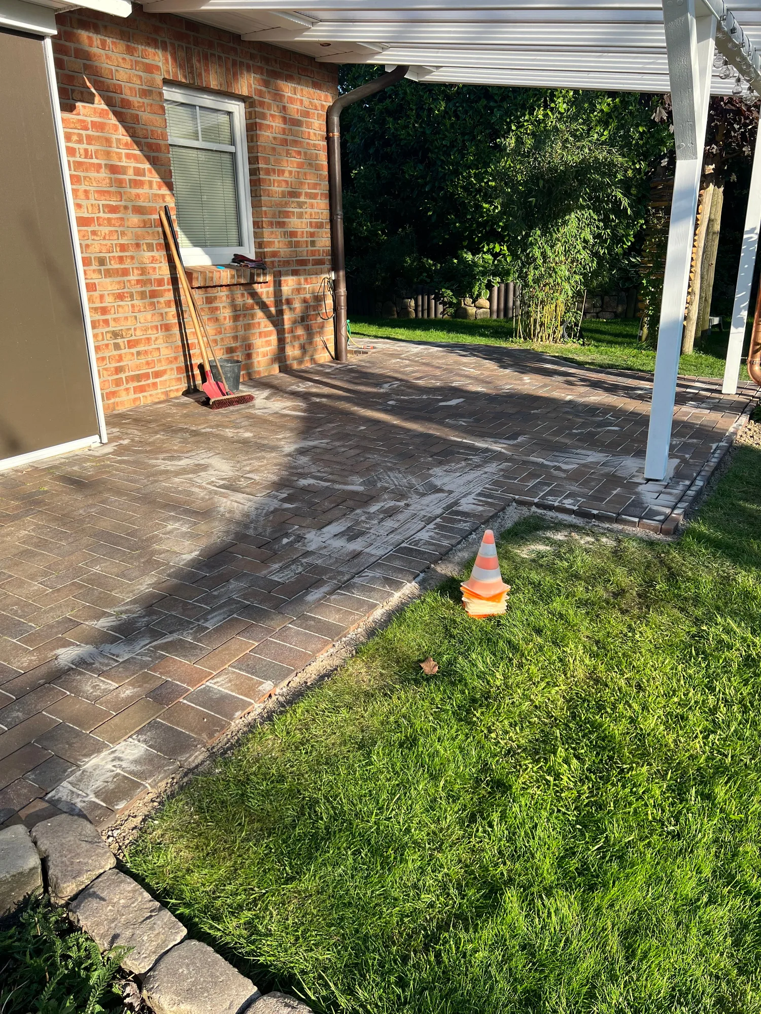 Gepflasterter Gartenweg an weißer Pergola