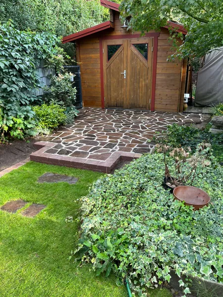 Fertige Polygonalplatten-Fläche mit Rasen und Gartenhaus